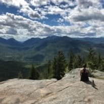 An Adirondack adventure photo of my daughter sitting atop one of the mountains in the Adirondacks overlooking the other mountains.